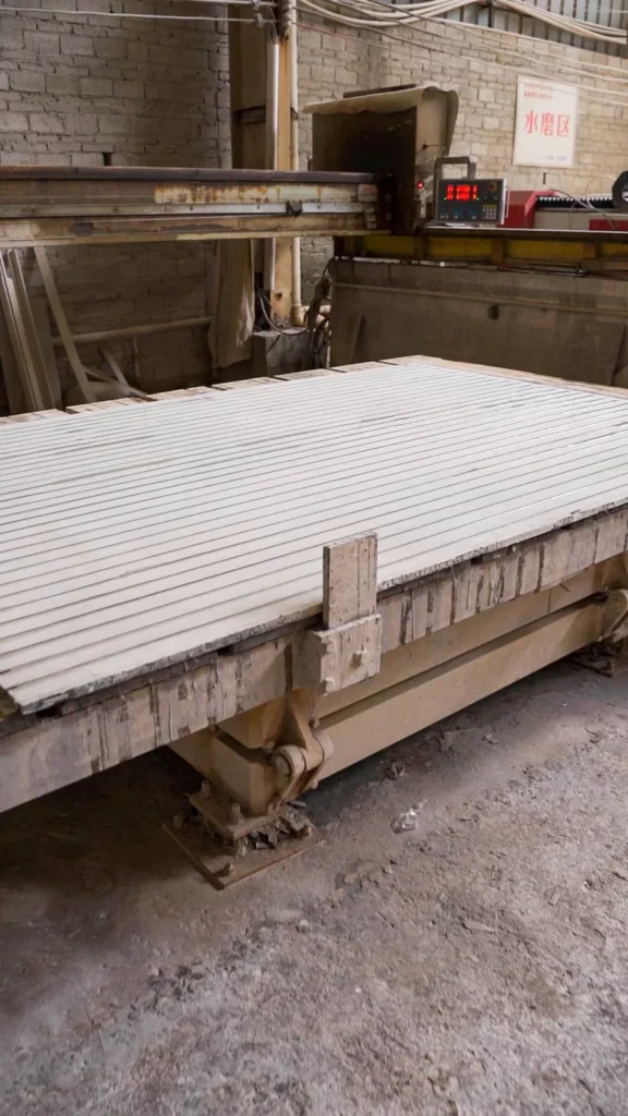 Long stone strips clamped on the edging machine while the edge profile is ground