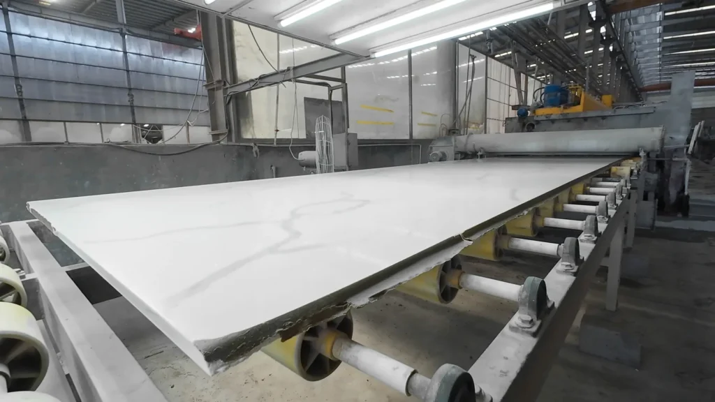 White slab with grey veins moving along the calibrating and polishing line in our slab workshop